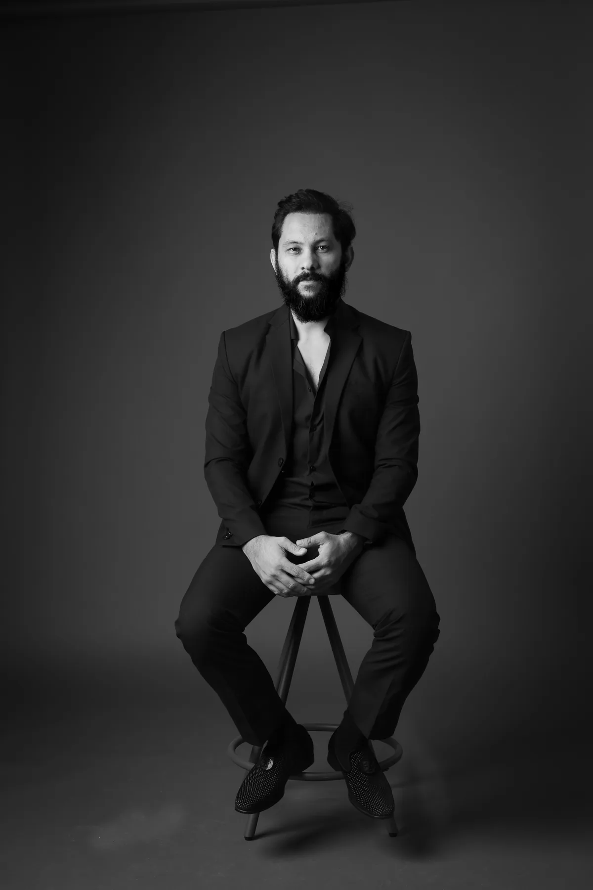 Studio portrait of Saurav MP seated in a dark suit